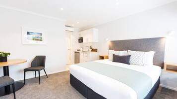 Una habitación de hotel moderna con una cama grande, un escritorio y una silla.