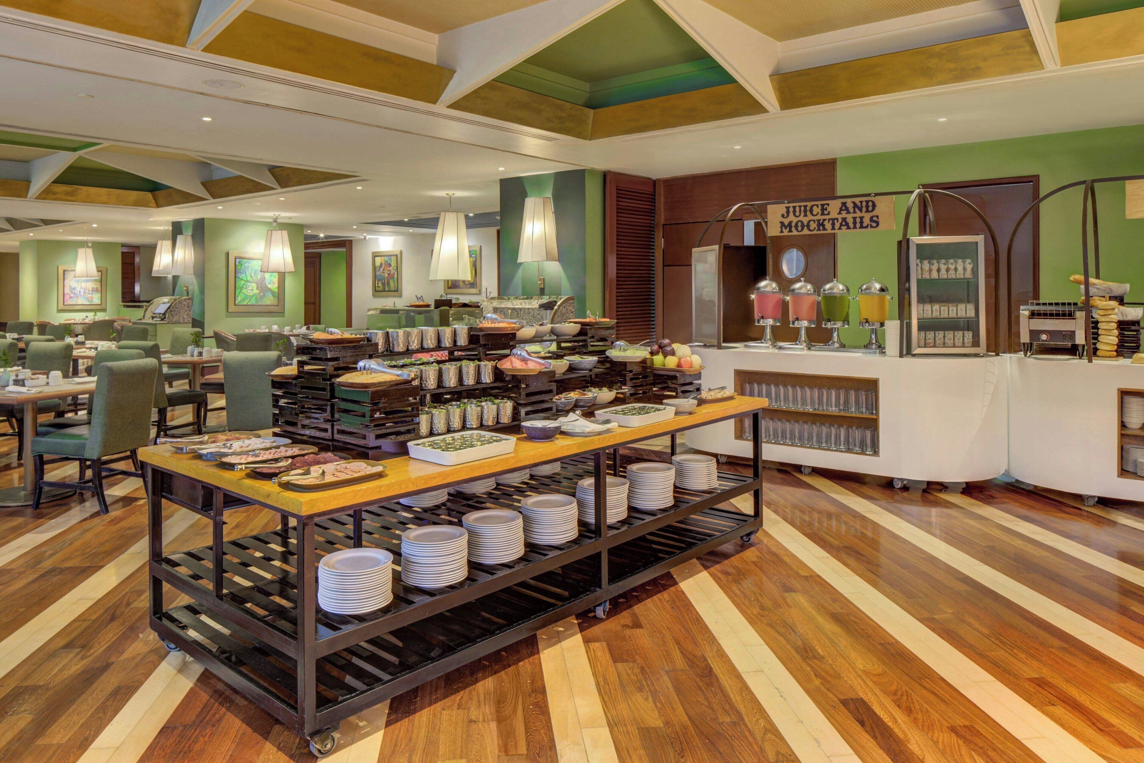 A buffet area with a variety of food items, a juice and mocktails station, and a seating area with tables and chairs.