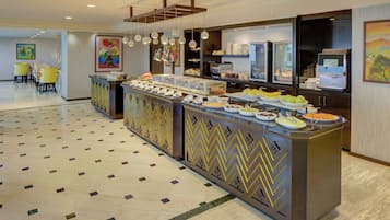 A buffet area with a variety of food items, a seating area with yellow chairs, and a patterned floor.