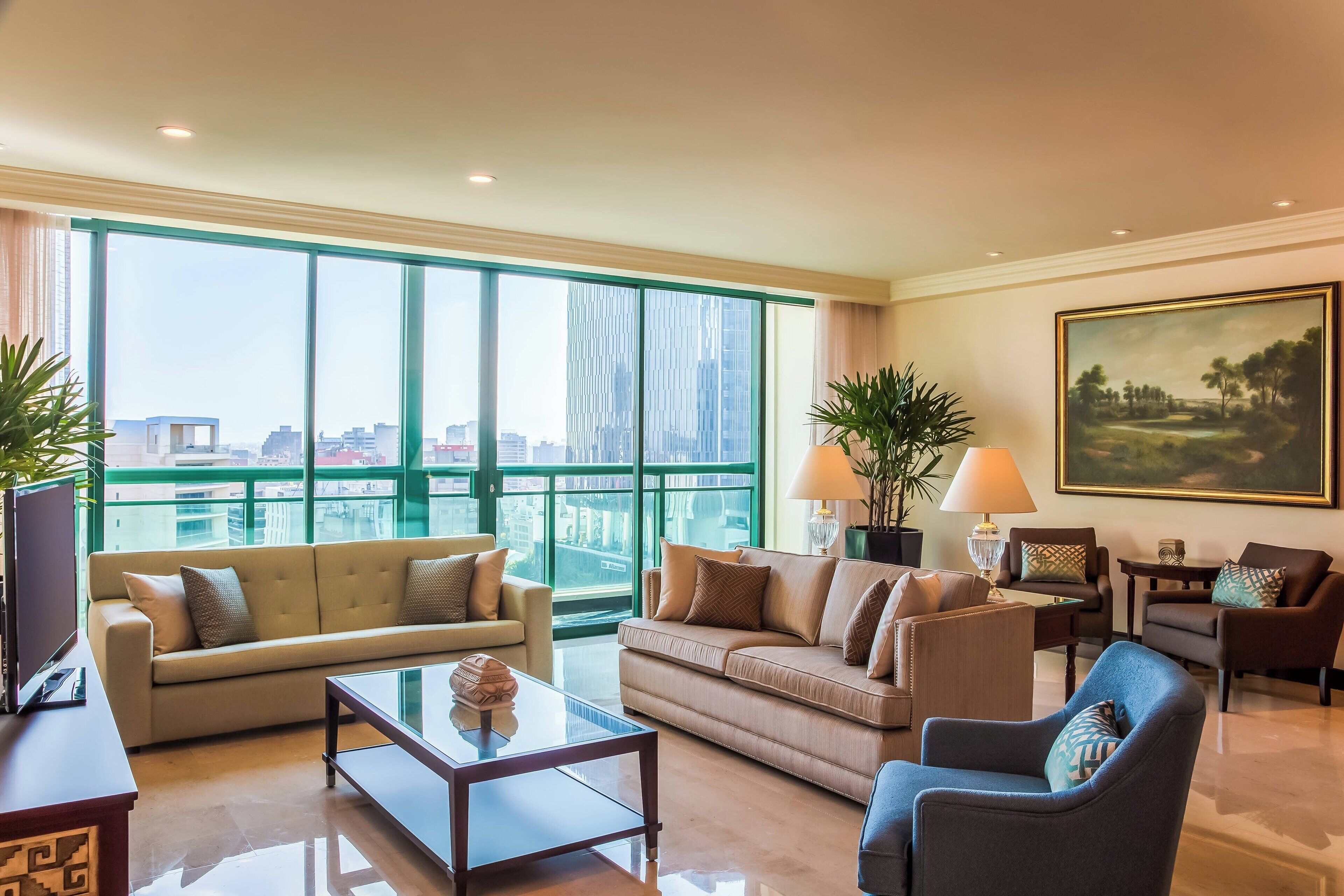 A spacious living room with a large window offering a city view, a sofa, a coffee table, and a chair.