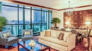 A spacious living room with a large window offering a city view, a chandelier, and a dining area with a wooden panel wall.