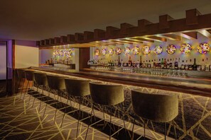 A bar area with a long counter, multiple stools, and a patterned carpet.
