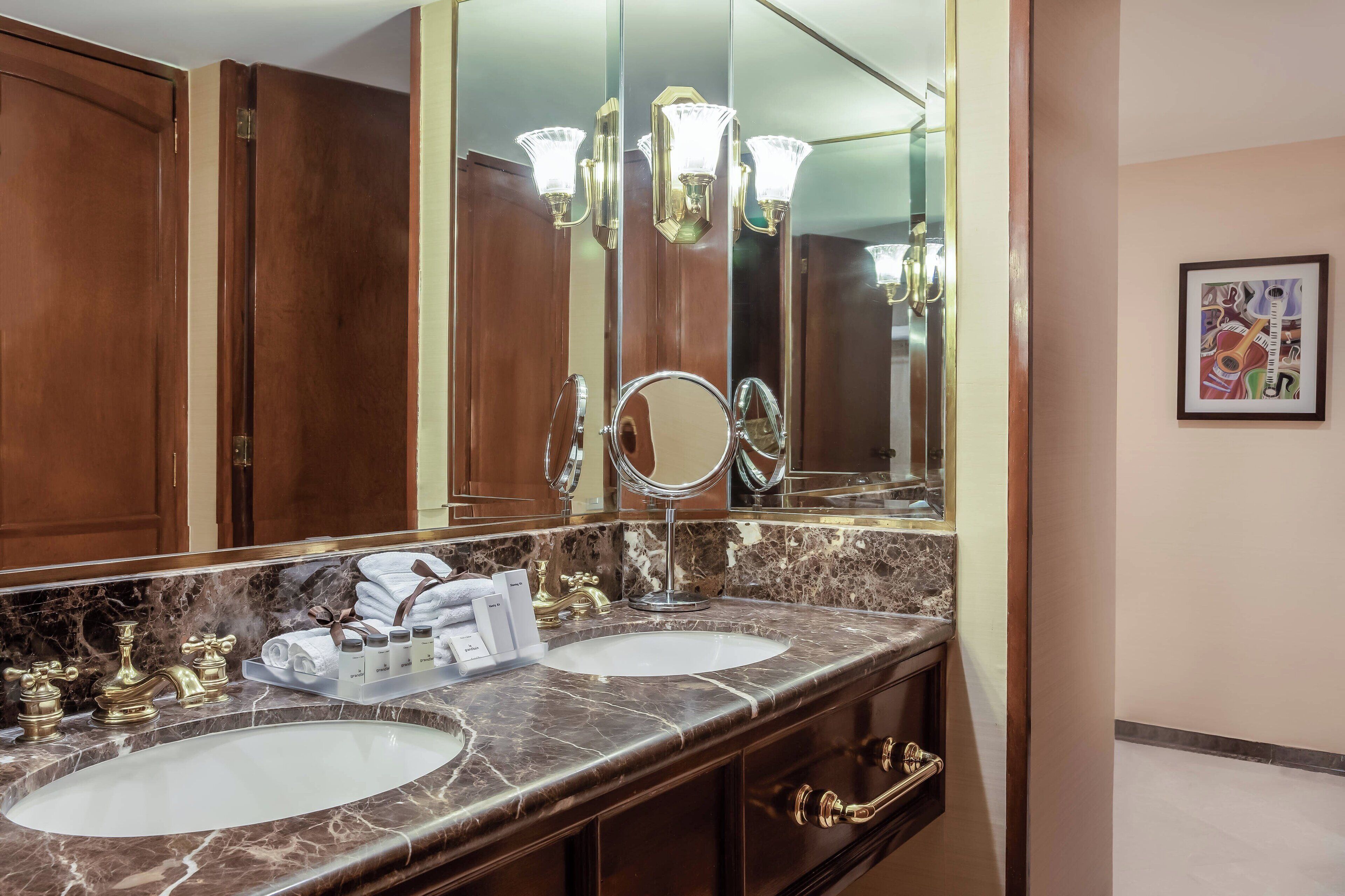 A bathroom with two sinks, a large mirror, and a vanity with a marble countertop.