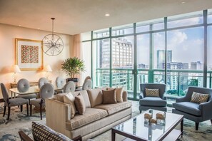 A spacious living room with a large window offering a city view, a dining area with a table and chairs, and a comfortable seating arrangement. - Sheraton Maria Isabel Mexico City Reforma (Mexico City)