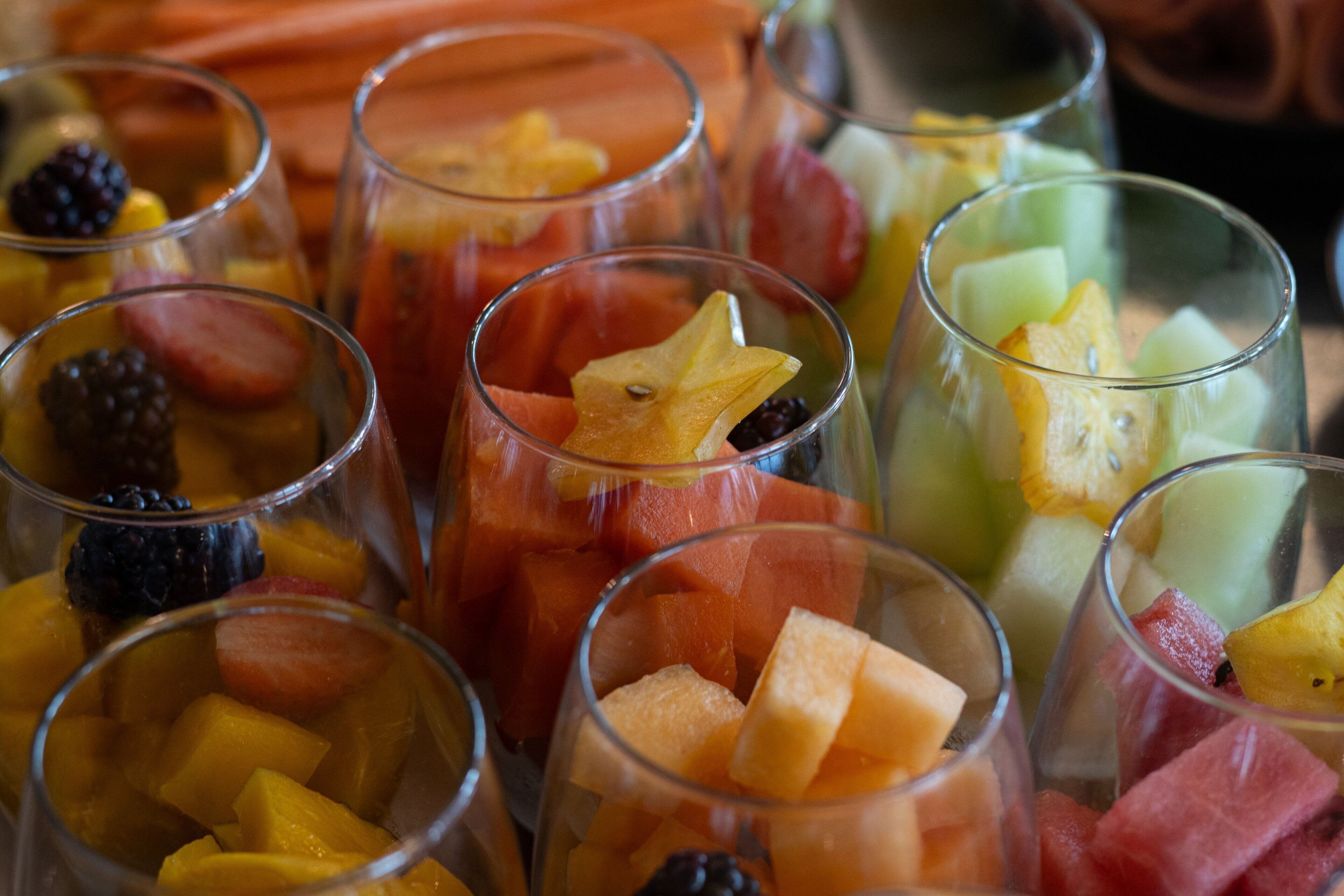Vasos transparentes con diversas opciones de fruta, como sandía, melón y bayas.