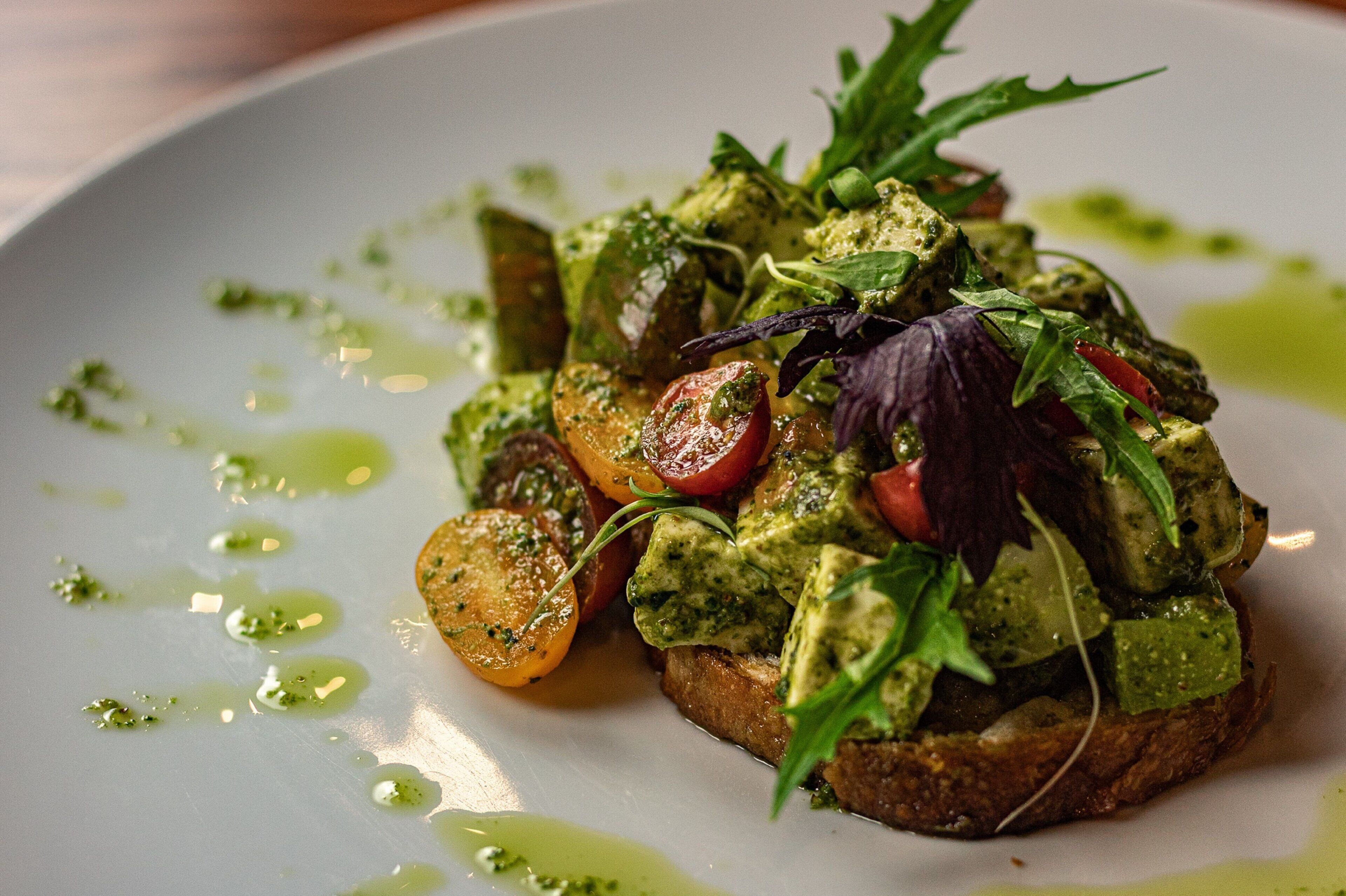 Un plat composé d’avocat, de tomates et de légumes verts, servi dans une assiette.