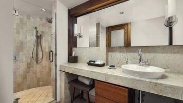 A modern bathroom with a glass-enclosed shower, a marble countertop, a large mirror, and a wooden vanity.