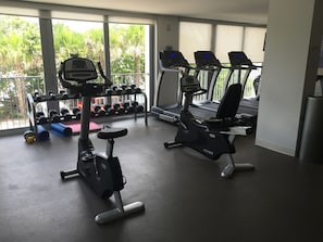 A gym with treadmills, an elliptical, and a rack of dumbbells.