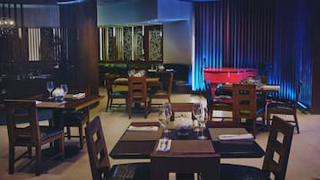 Ein Restaurant mit Tischen, Stühlen, einem Klavier und einer Bühne mit Vorhängen.