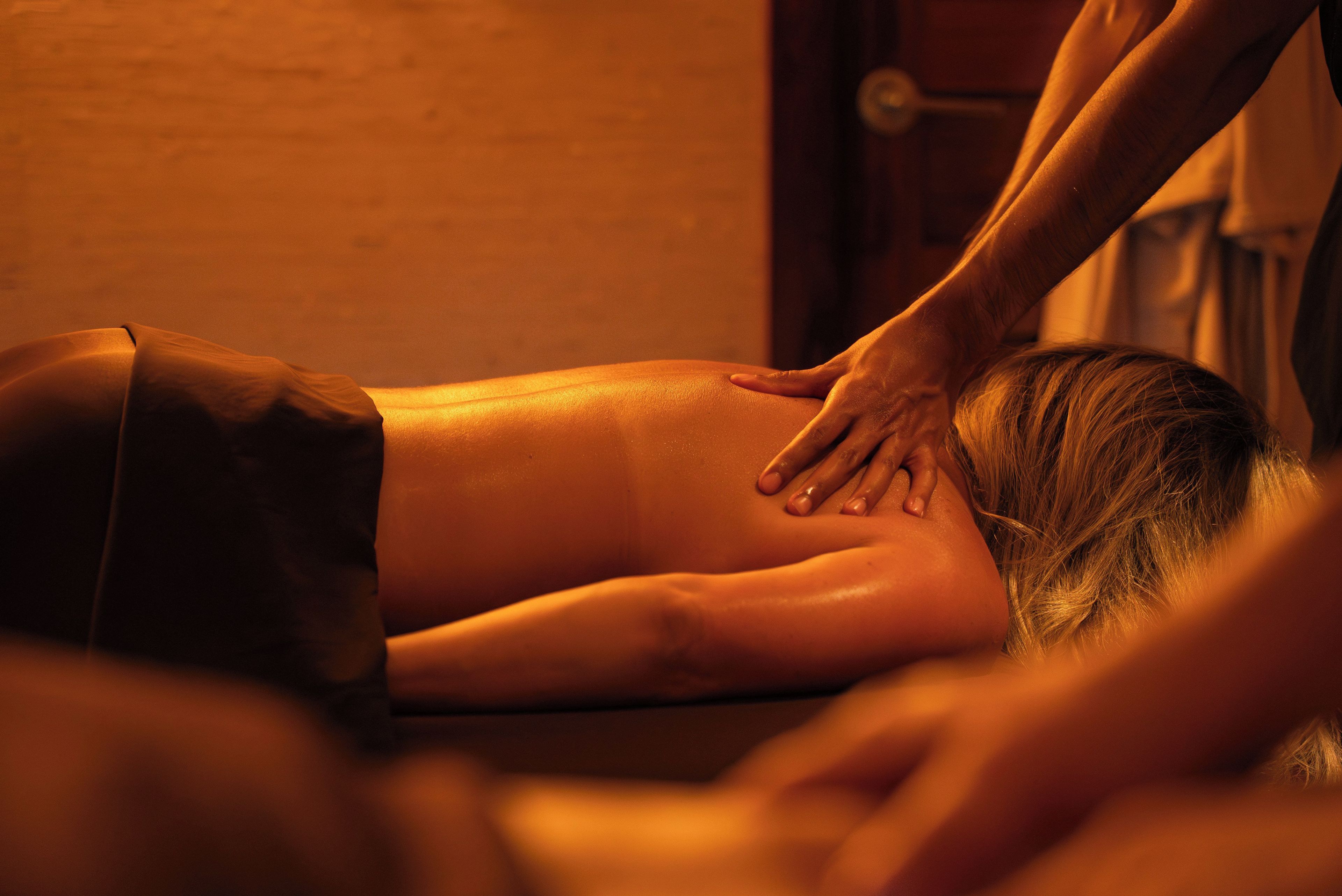 A person receiving a massage in a room with a wooden floor and a door in the background.
