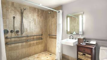 A modern bathroom with a walk-in shower, grab bars, a sink with a mirror, and a toilet.