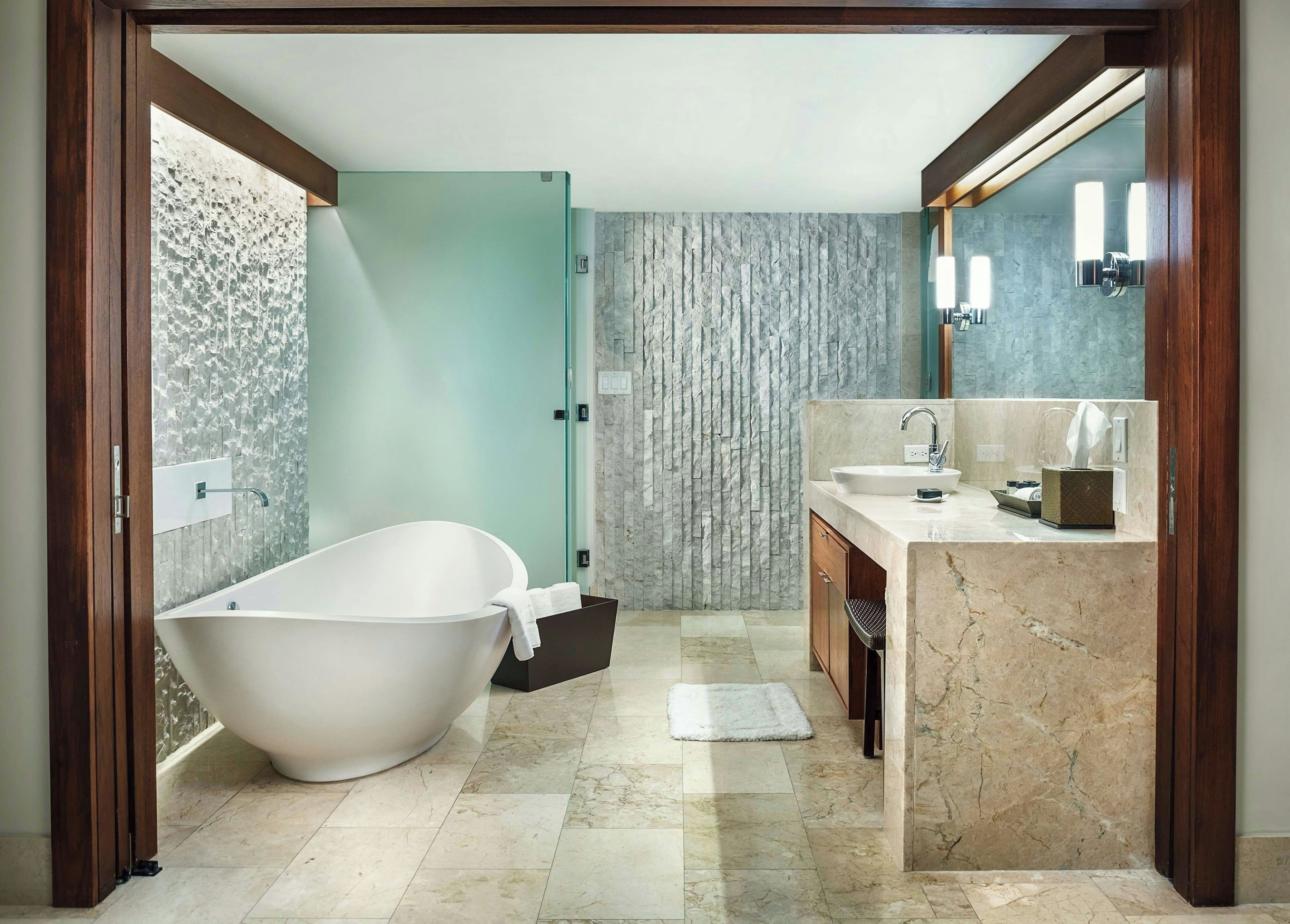 A modern bathroom with a freestanding bathtub, a vanity with a sink and mirror, and a textured wall.