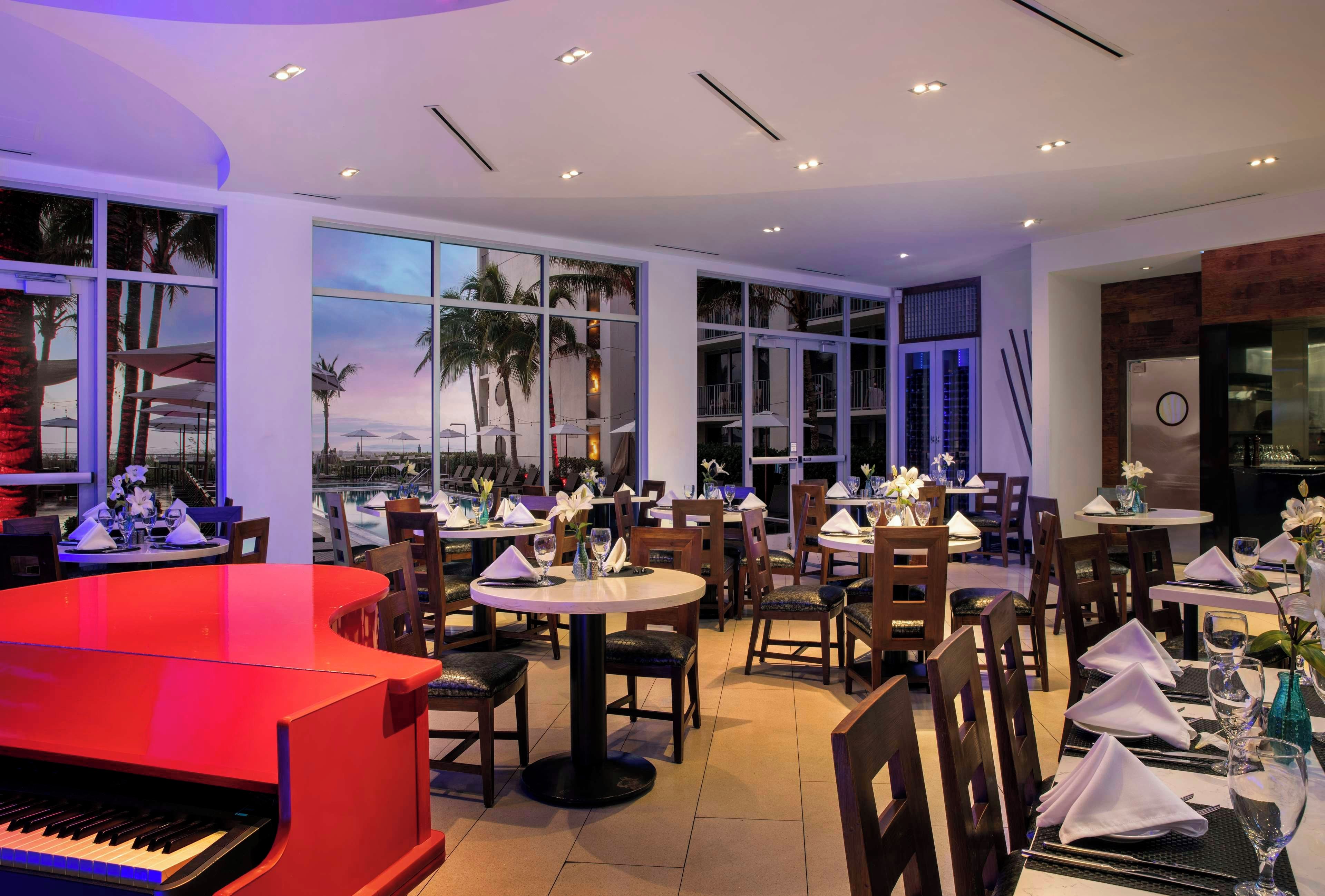 Un restaurante con varias mesas, sillas y un piano.