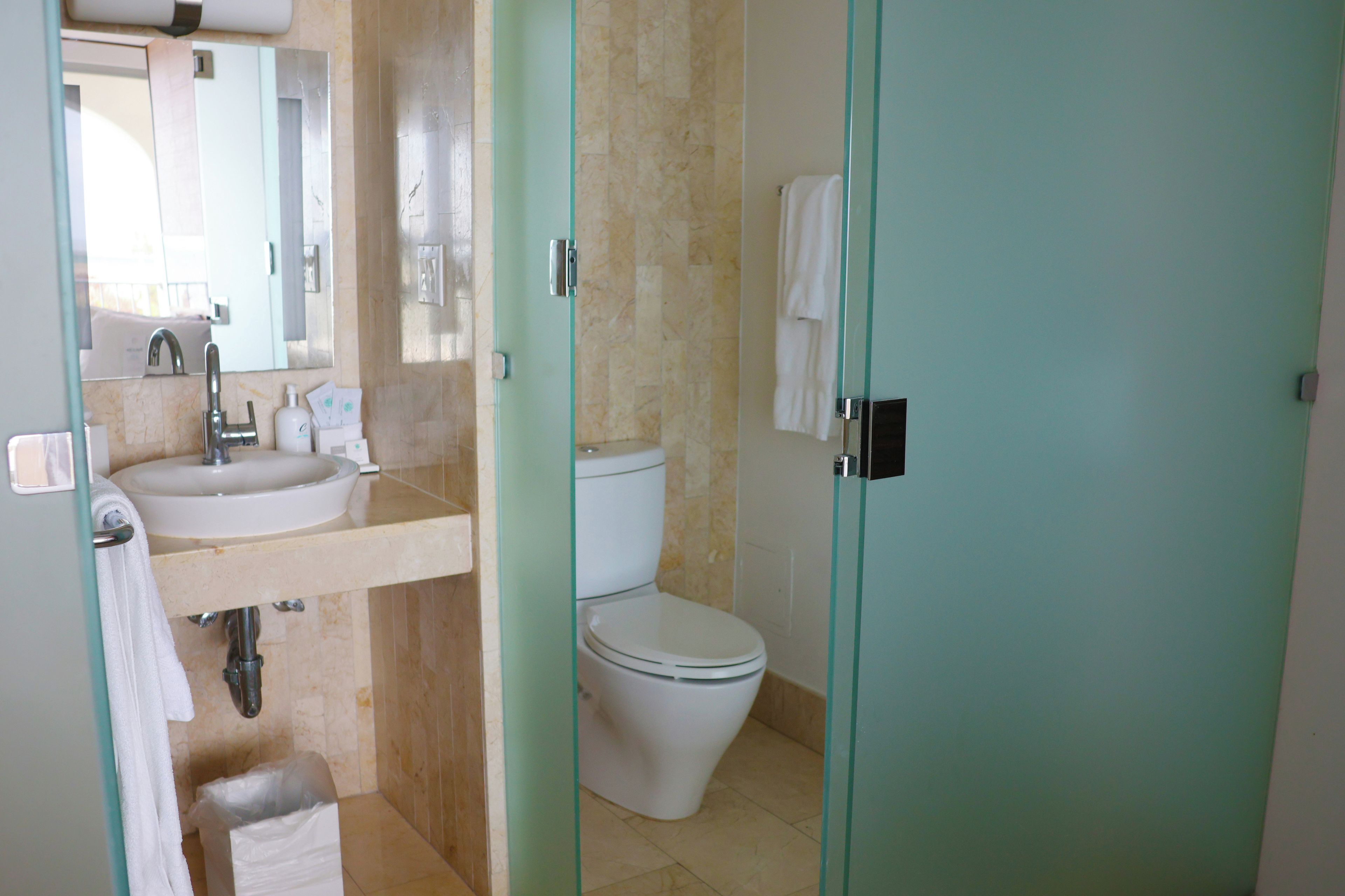 A bathroom with a sink, mirror, toilet, and glass shower enclosure.
