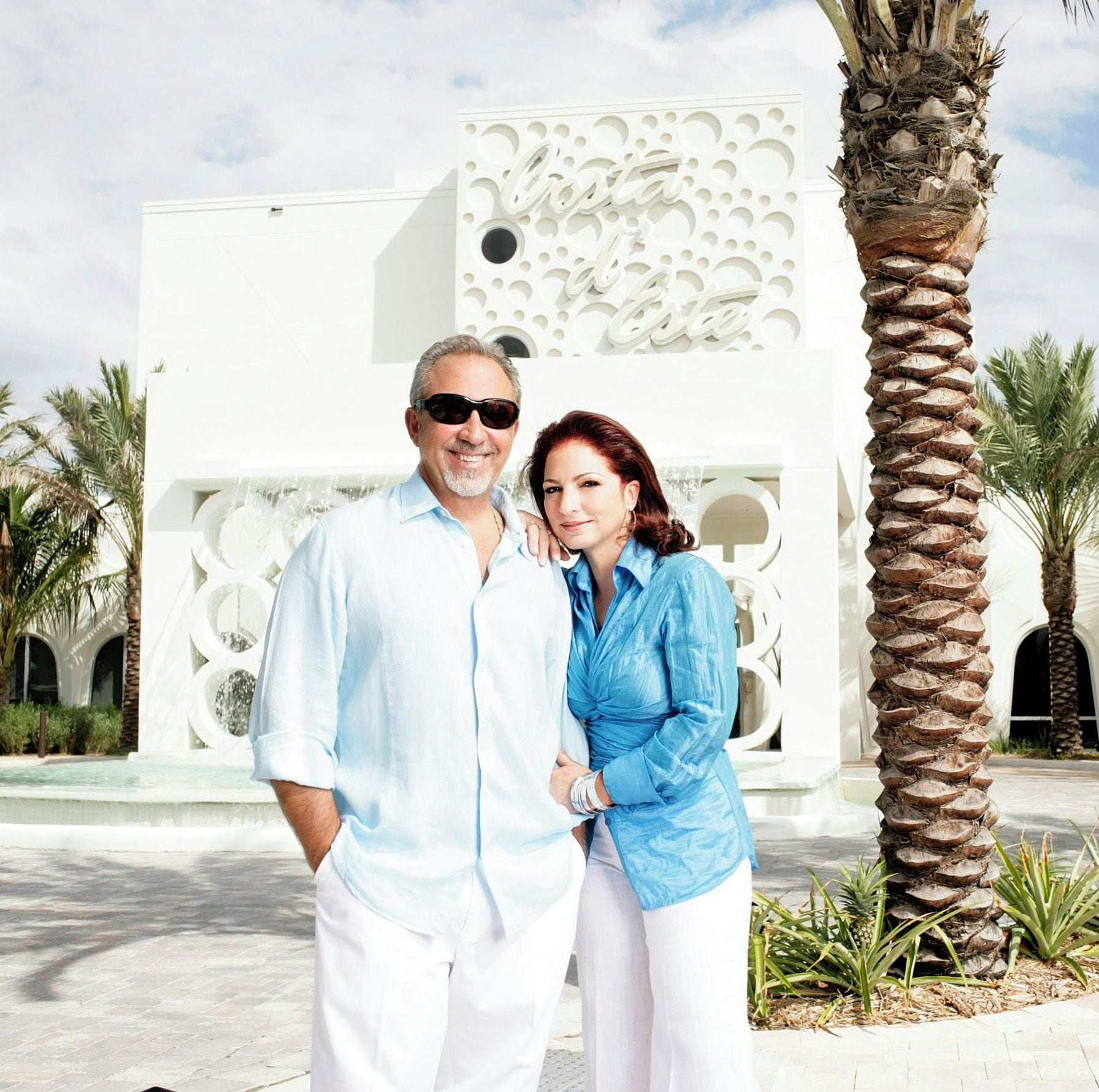 A man and a woman standing in front of a white building with a decorative facade.