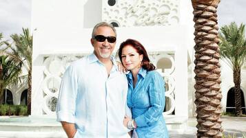 A man and a woman standing in front of a white building with a decorative facade.
