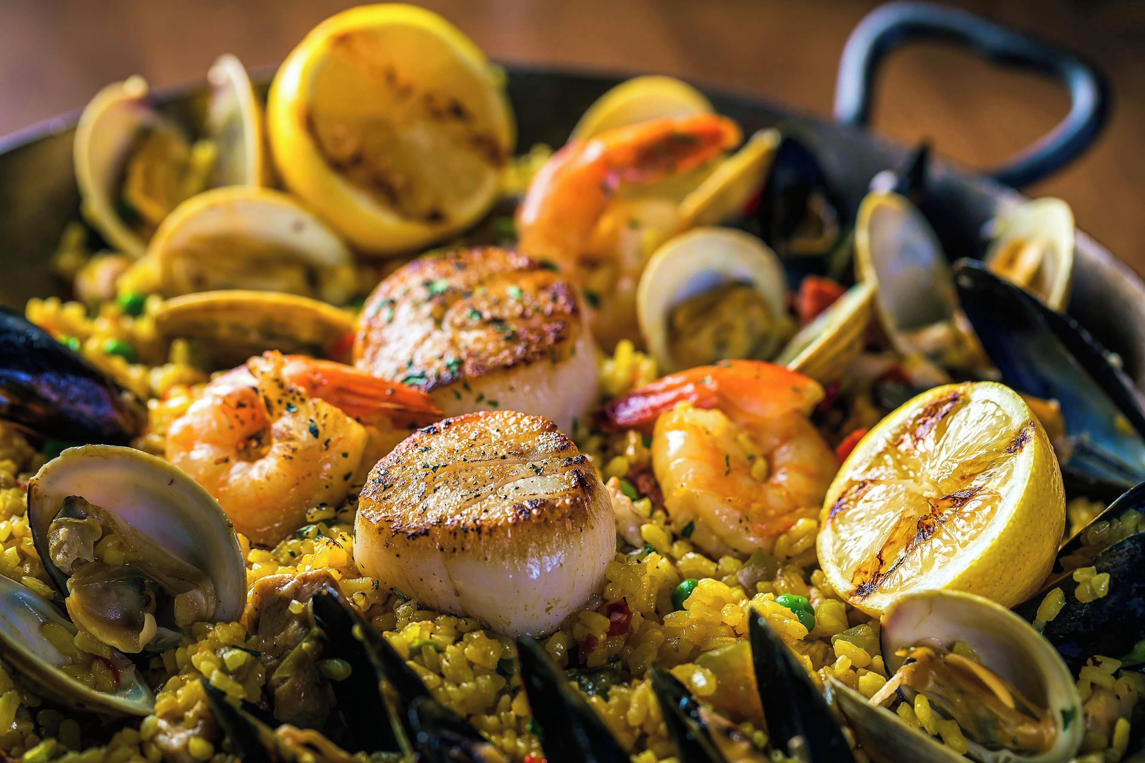 Una paella de mariscos con camarones, mejillones y rodajas de limón.