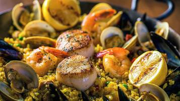 Una paella de mariscos con camarones, mejillones y rodajas de limón.