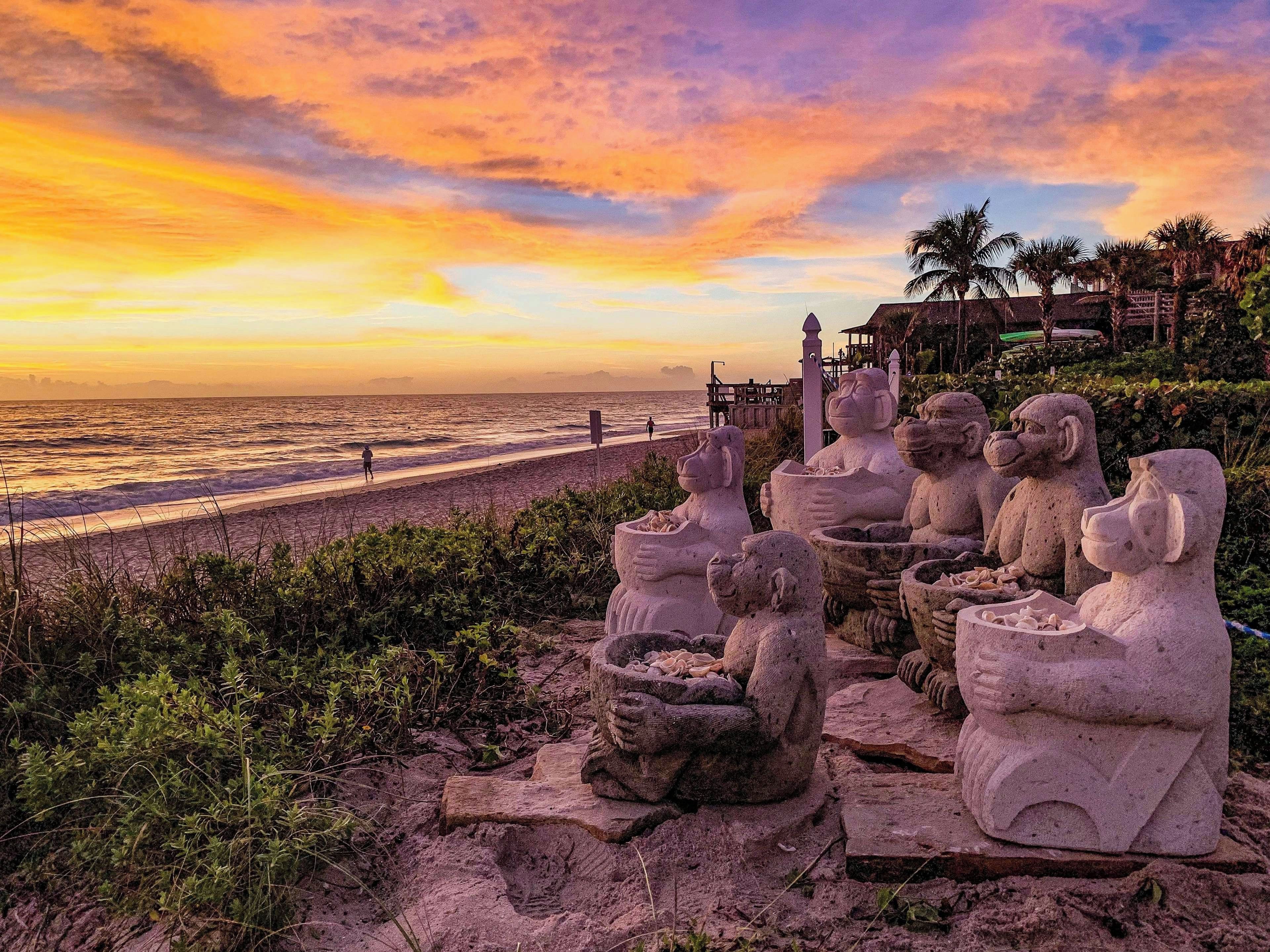 A beach with stone sculptures and a sunset view.