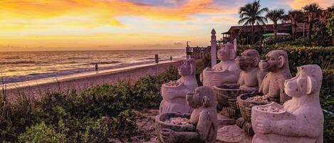 A beach with stone sculptures and a sunset view.