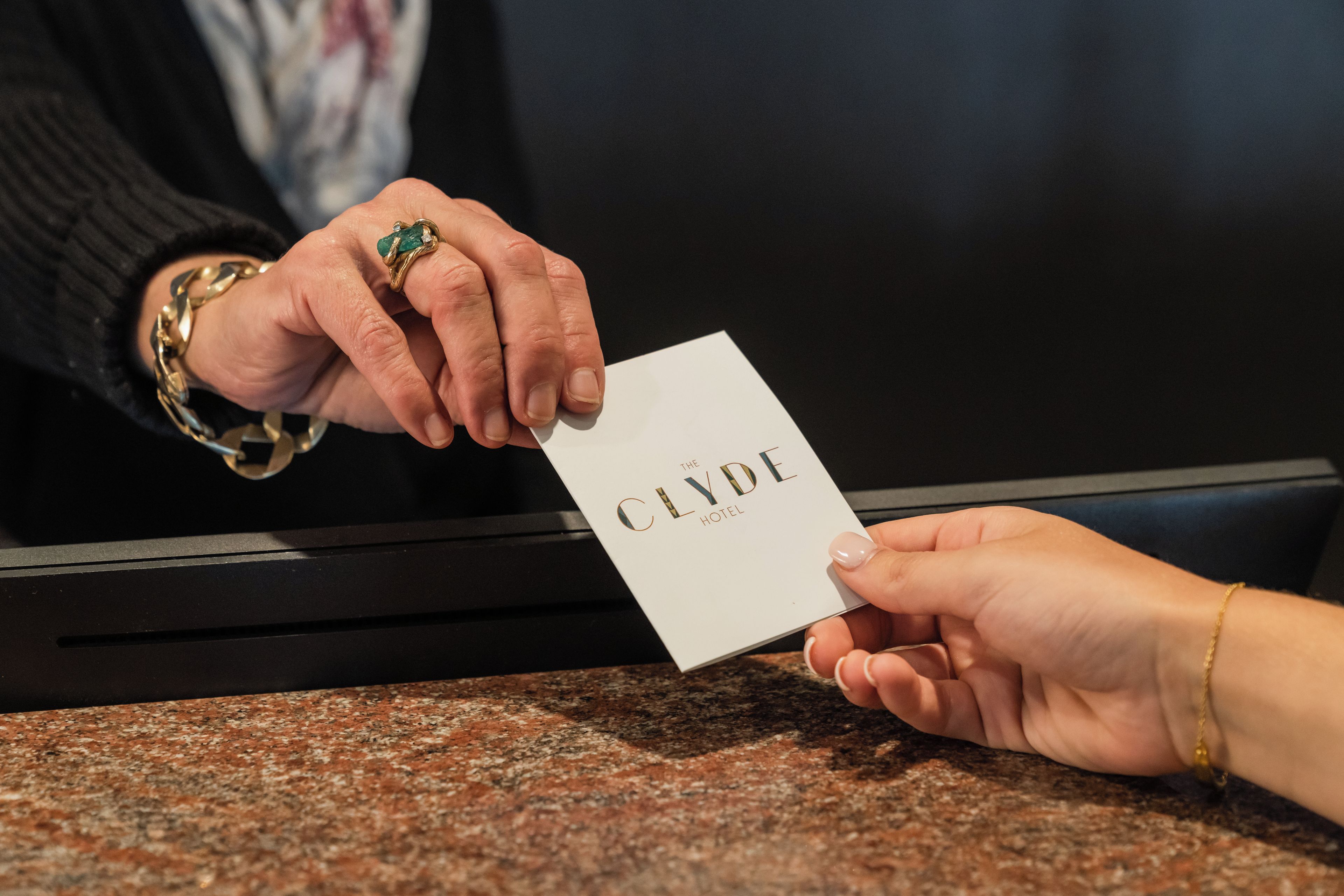 A person handing over a business card to another person at a counter.