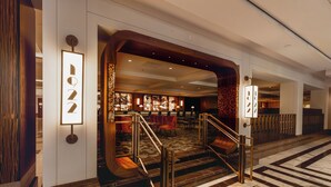 Un vestíbulo de hotel con una imponente escalera, una recepción y un área de estar con sillas y mesas.