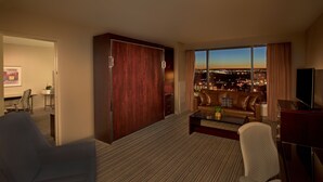 Habitación de hotel con vista a la ciudad, una cama grande, un escritorio y un televisor.