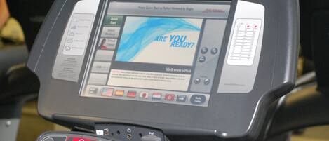 A treadmill with a digital display and control panel.