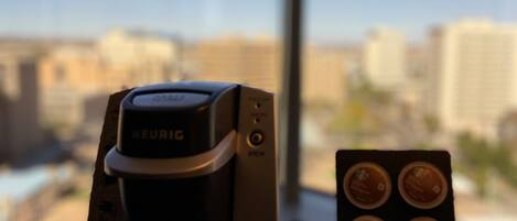 Eine Kaffeemaschine von Keurig auf einem Tisch mit Blick aus dem Fenster auf eine Stadtlandschaft.