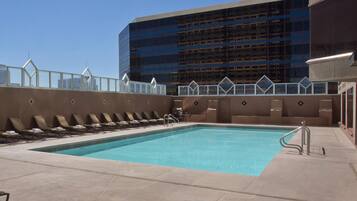 A rooftop pool with lounge chairs and a view of a modern building.