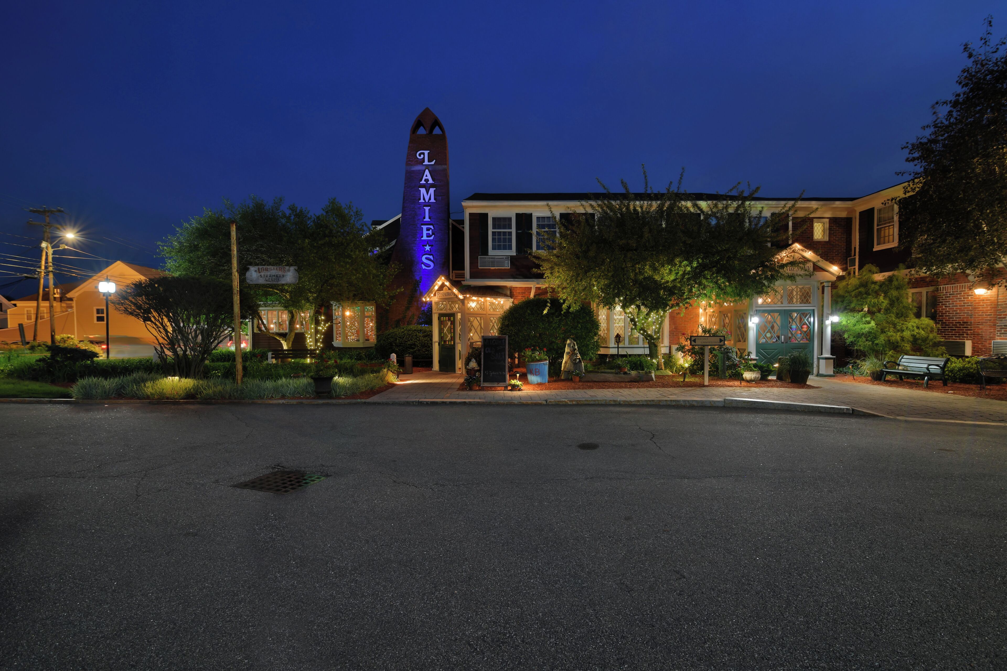A building with a prominent sign, a well-lit entrance, and a paved area in front.