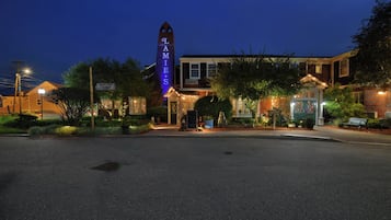 A building with a prominent sign, a well-lit entrance, and a paved area in front.
