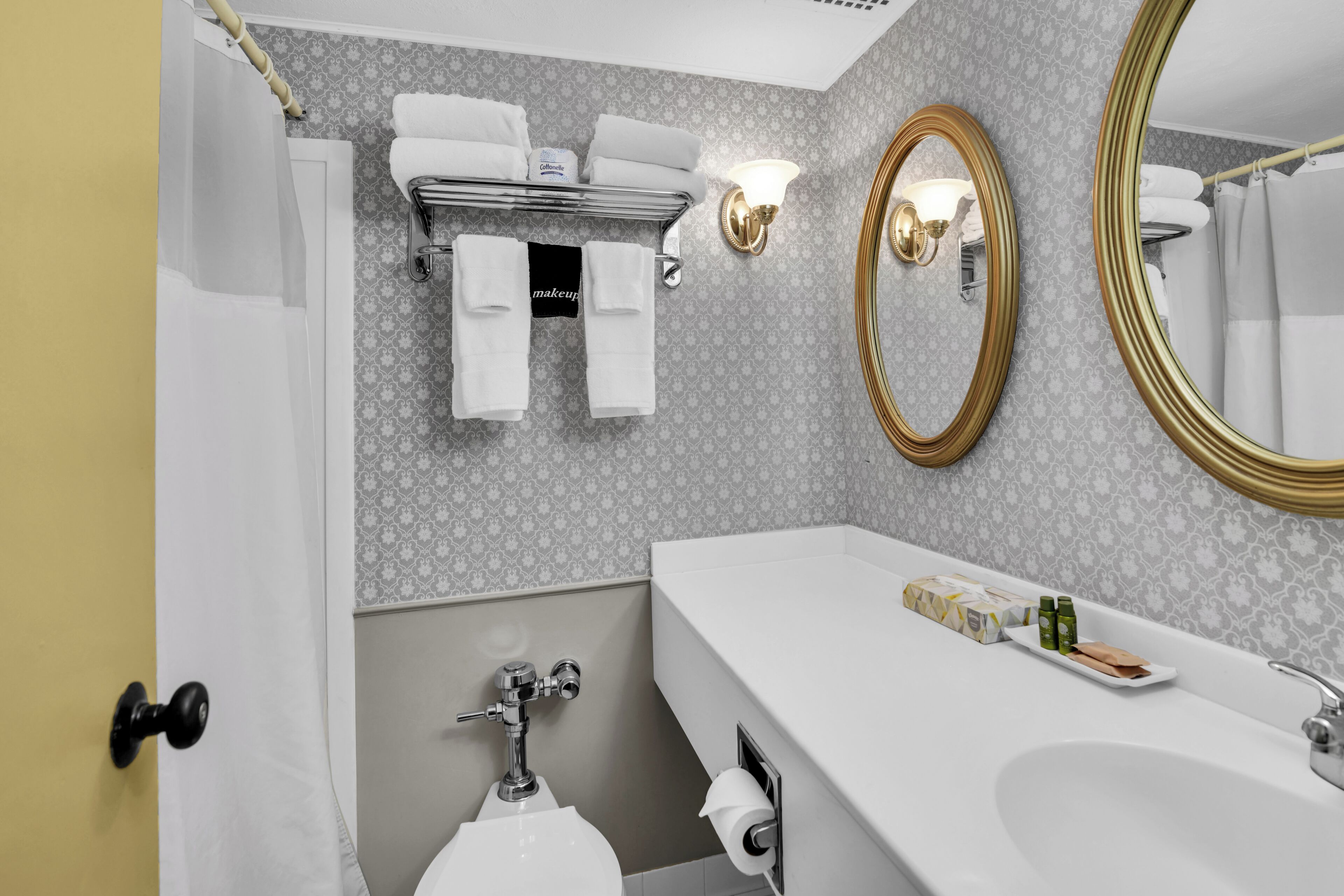 A bathroom with a white sink, a mirror, a towel rack, and a toilet.