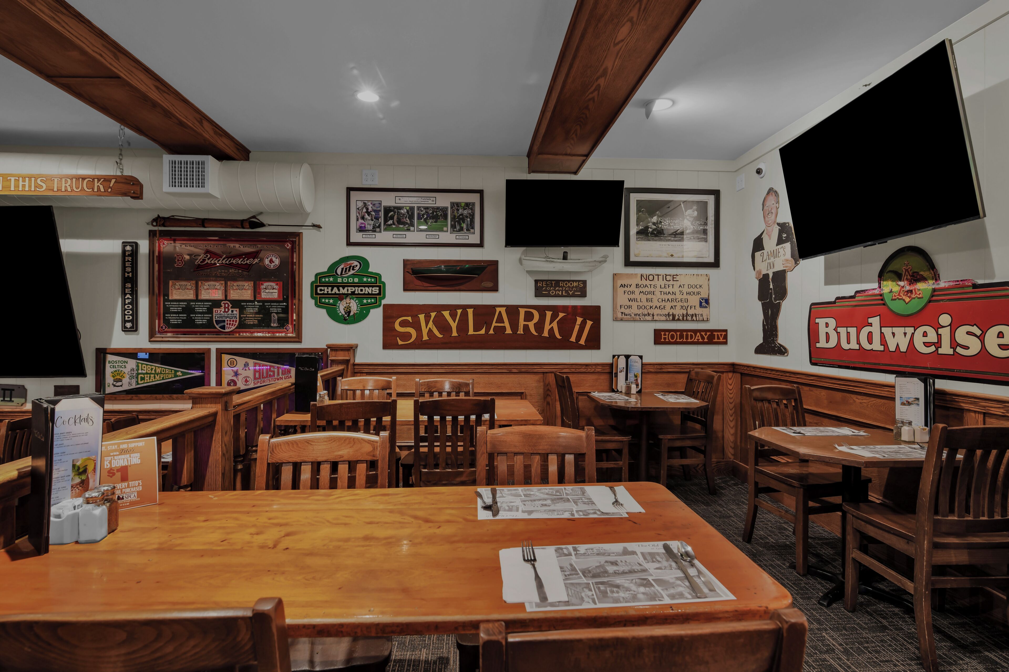 En restaurang med träbord och stolar, inramade minnessaker på väggarna och en Budweiser-skylt.