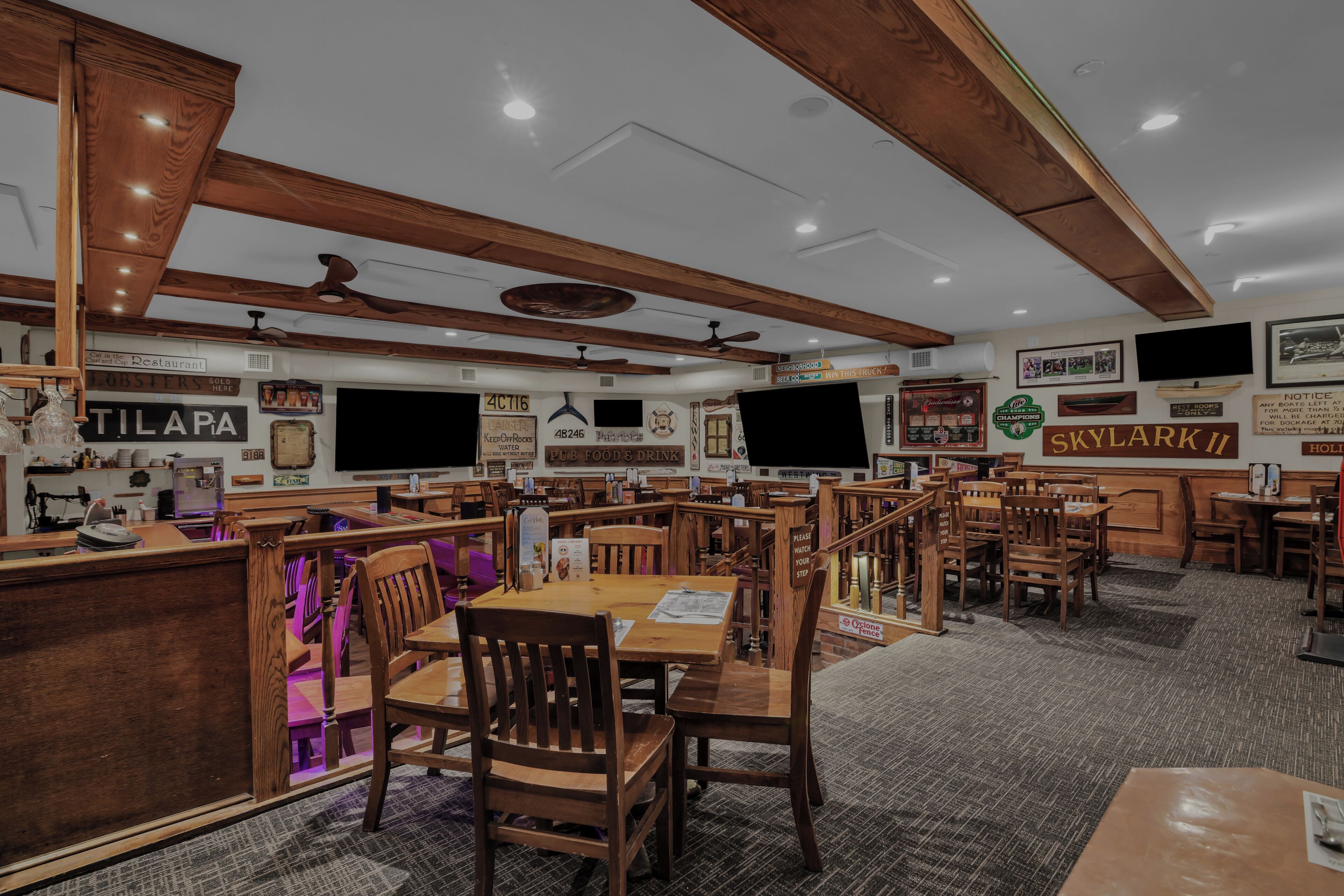 A restaurant with wooden furniture, ceiling fans, and various signs on the walls.