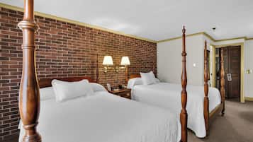 A hotel room with two beds, a brick wall, and a wooden door.