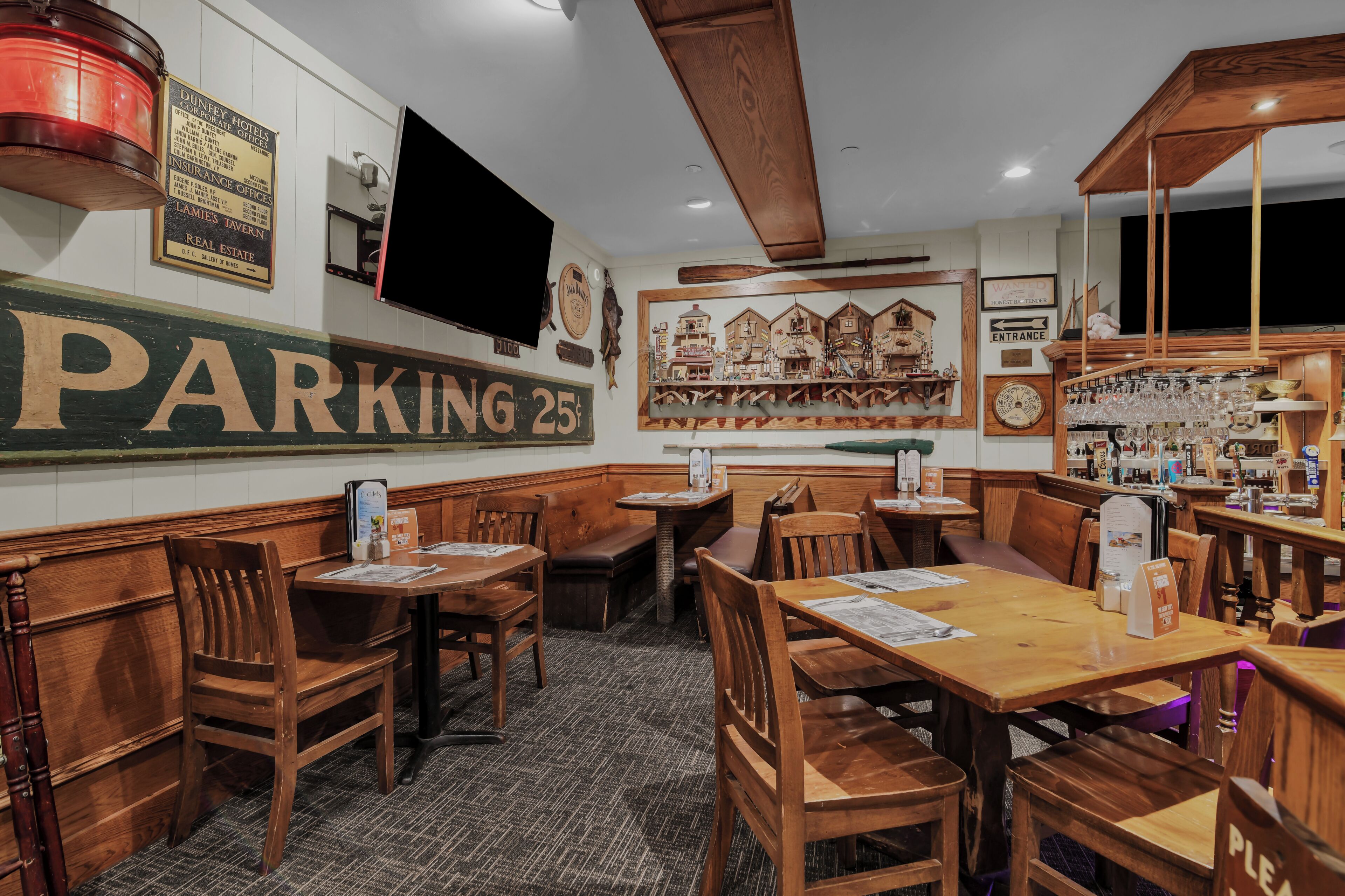 Un restaurant avec des meubles en bois, une grande enseigne indiquant « PARKING 25 ¢ » et un téléviseur fixé au mur.