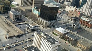 An aerial view of a cityscape with various buildings, including a parking lot with multiple cars and a large building with a distinctive black facade. - Holiday Inn Columbus Dwtn-Capitol Square by IHG (Columbus)