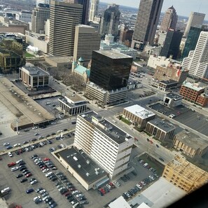 Une vue aérienne d’une ville, avec différents bâtiments, dont un parking rempli de voitures et un grand immeuble doté d’une façade noire remarquable.
