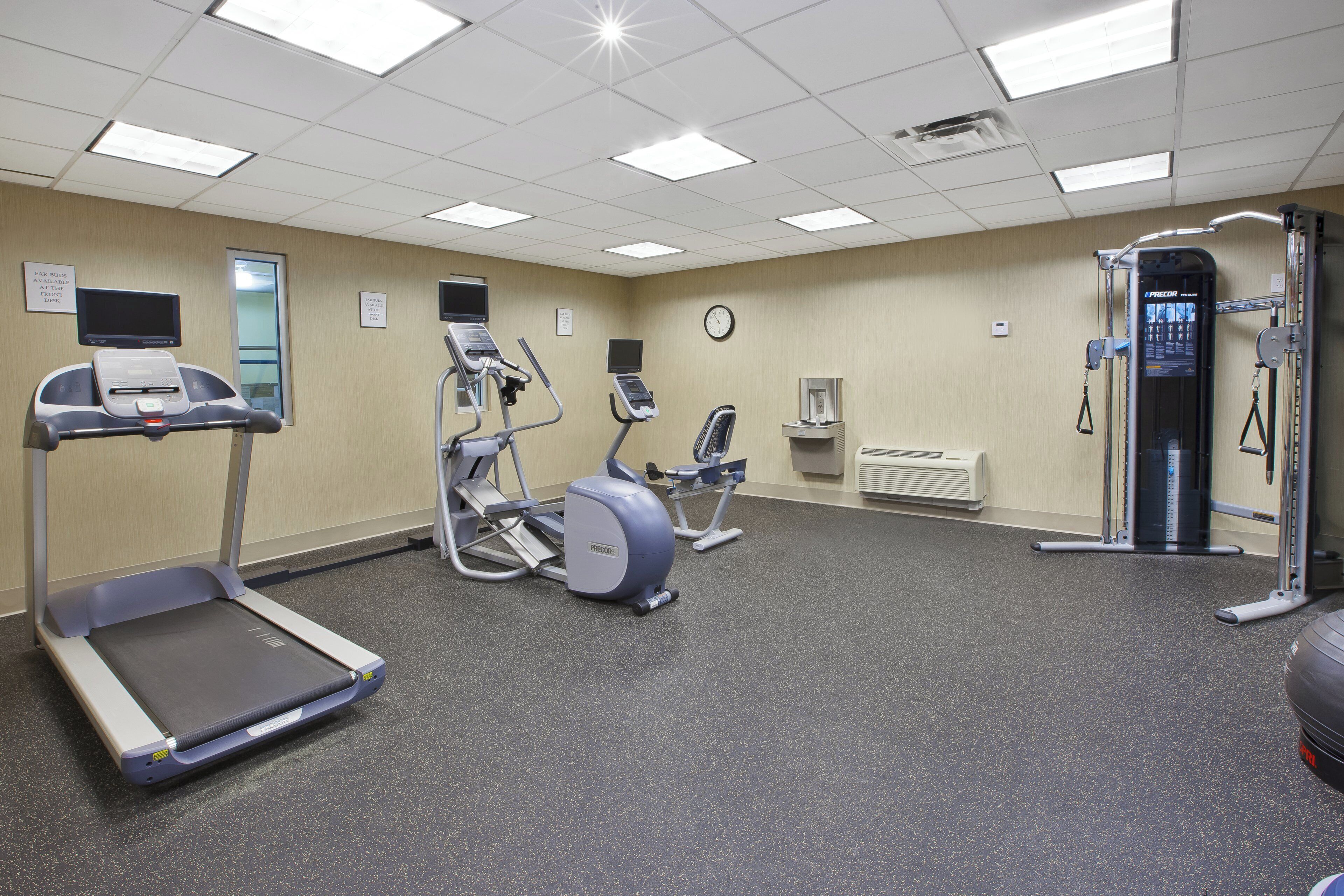 Un gimnasio equipado con cintas de correr, elípticas, una bicicleta estática y máquinas de pesas.