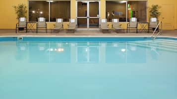 A swimming pool with lounge chairs and a door leading to an indoor area.