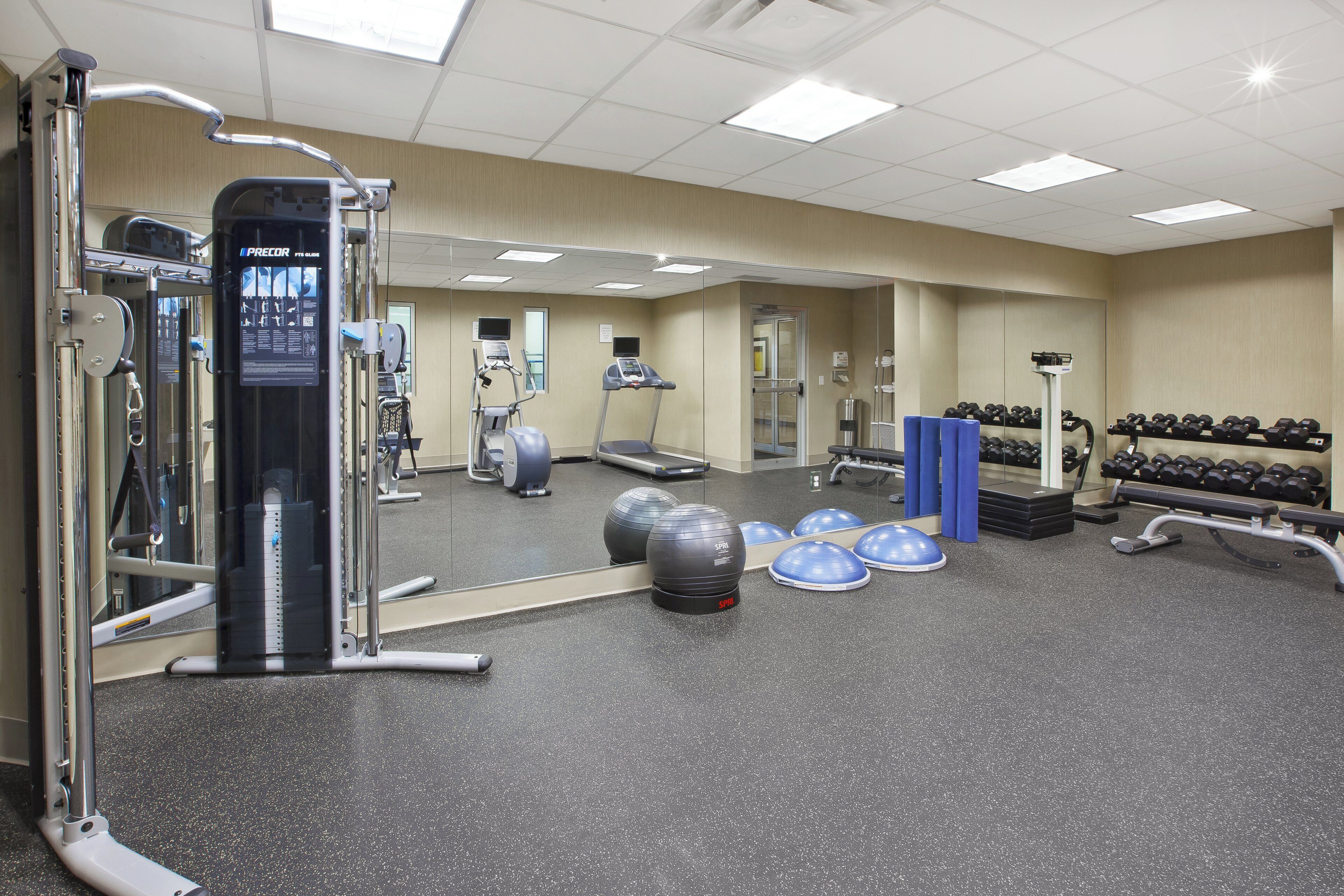 Une salle de sport équipée de matériel d’exercice, d’un miroir et d’haltères.