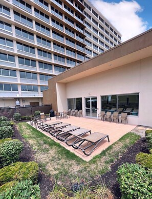 Un bâtiment moderne doté d’un espace patio sur le toit, comprenant des chaises longues et des sièges d’extérieur.