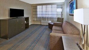 A hotel room with a flat-screen TV, a sofa, a small table, and a large window with curtains. - Holiday Inn Columbus Dwtn-Capitol Square by IHG (Columbus)