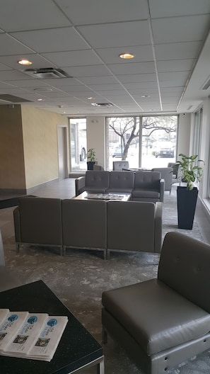 A modern waiting area with a sofa set, a coffee table, and a small table with newspapers.