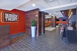 A modern interior with a prominent 'BURGER THEORY' sign, a reception area, and a seating area with a bar.