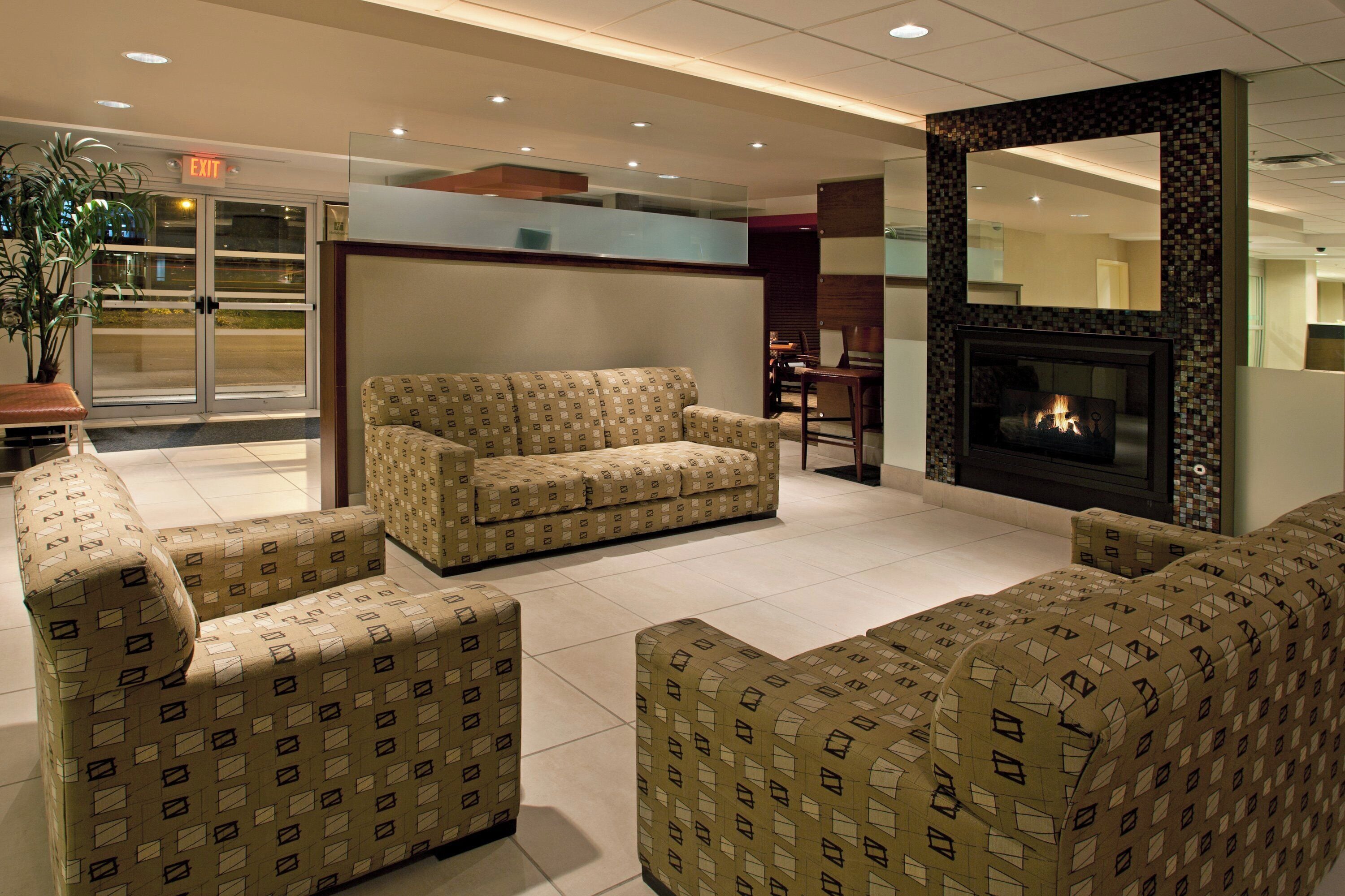 A modern living room with a sofa set, a fireplace, and a glass partition.