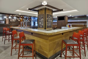 A bar area with a central island, multiple seating options, and a variety of beer taps.