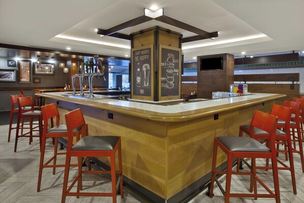 A bar area with a central island, multiple seating options, and a variety of beer taps.