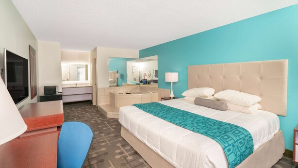 Ein Hotelzimmer mit Bett, Schreibtisch, Stuhl, Fernseher, Badezimmer und Spiegel.